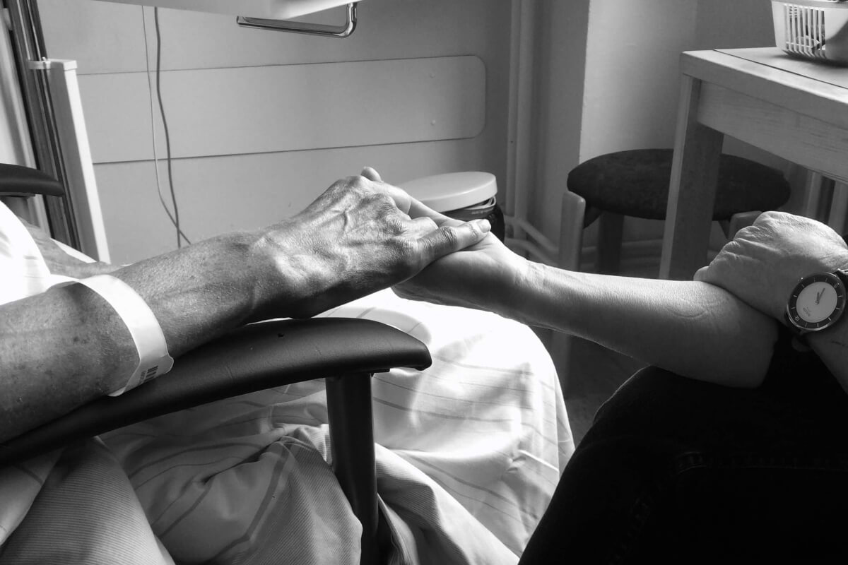 Ein Foto aus dem Krankenhaus. Man sieht die Hände von Dirk und Cordula, die sich gegenseitig halten